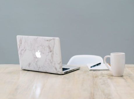 mac on desk with mug, notebook and pen